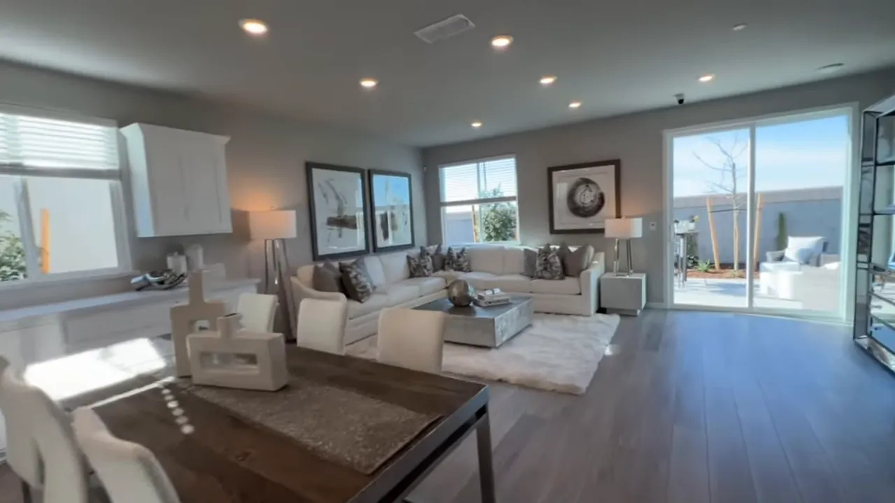Open kitchen and dining area with large stone island, dark cabinetry and light wood-look flooring