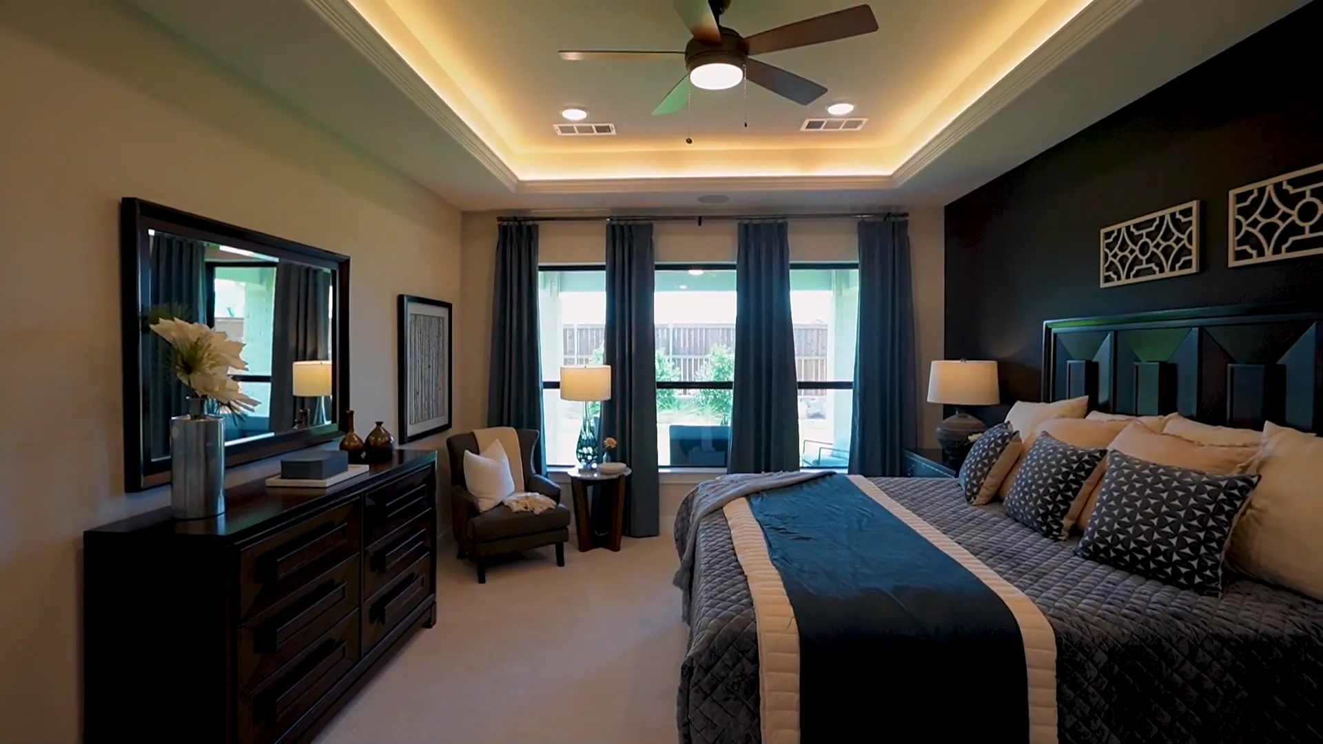 Primary suite bedroom with tray ceiling and large windows