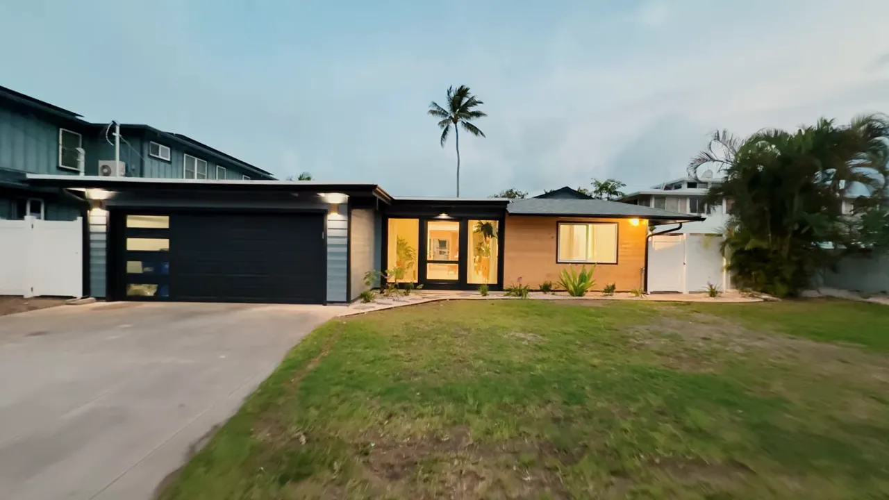 Renovated single-family home in Kailua, Hawaii with garage, front lawn, and ocean-tropical landscaping