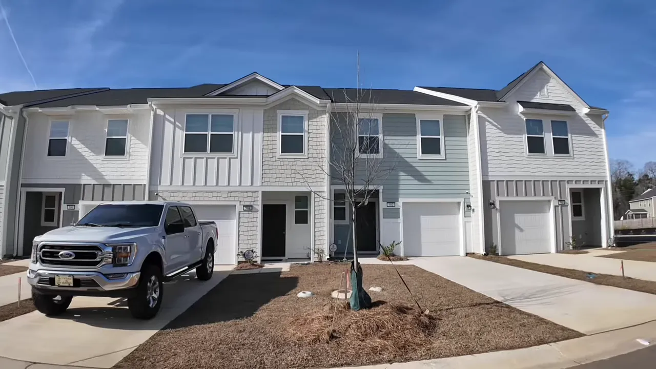Finished townhome model front with one-car garage, driveway and small yard in Monk's Corner