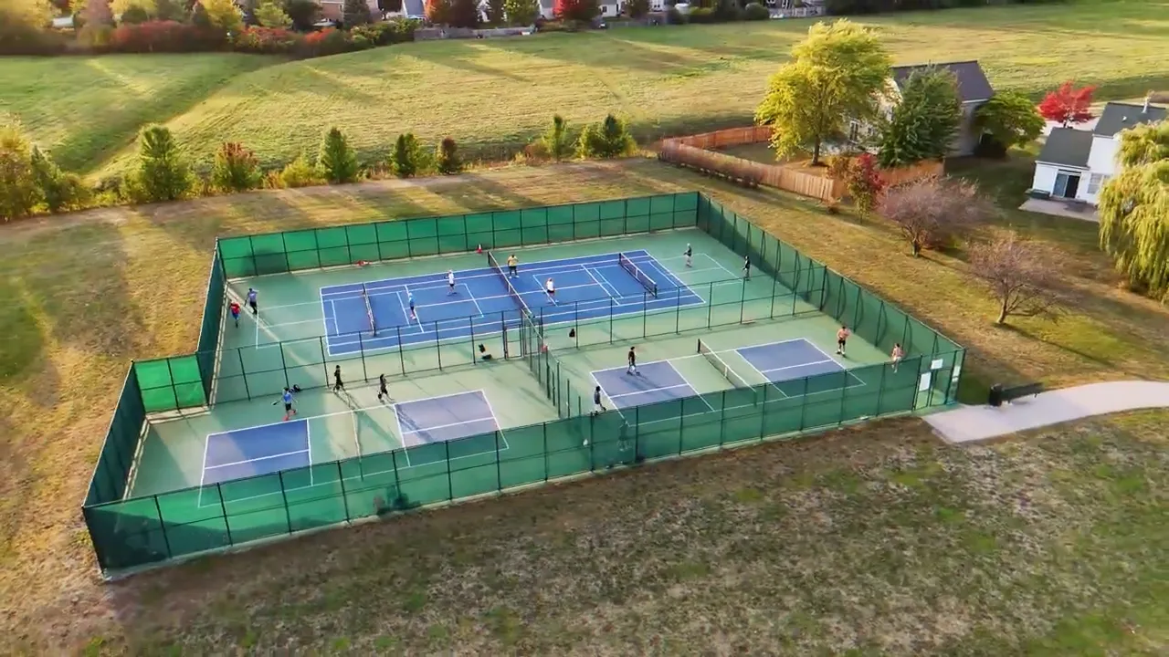 Aerial view of fenced pickleball courts near homes