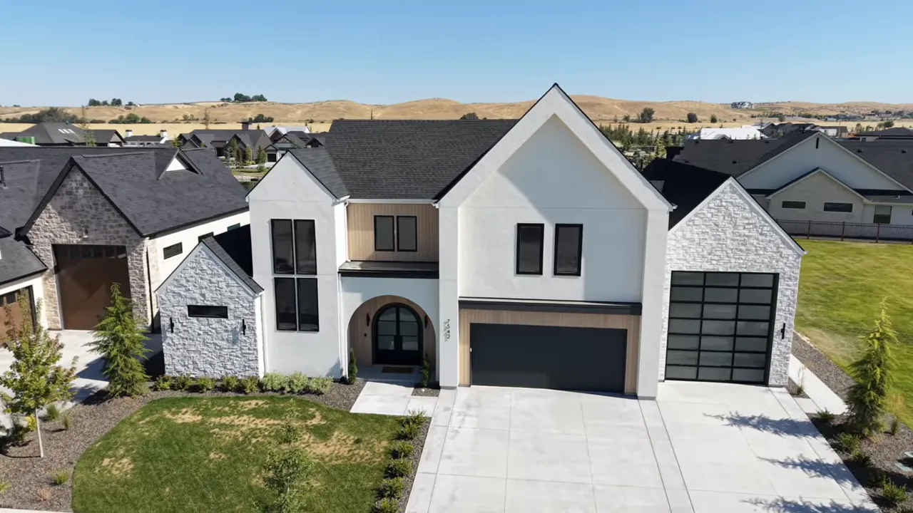 Front exterior of white custom home with stone archway and tall garage doors