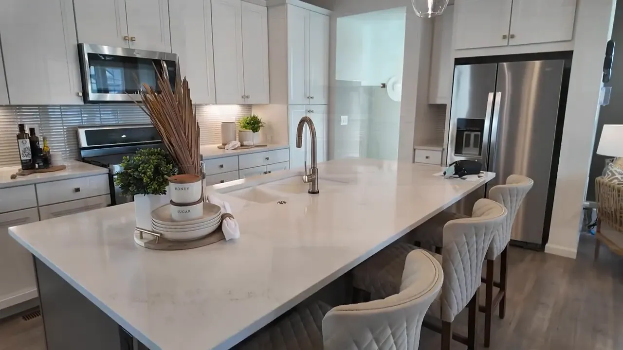 Aurora Highlands Crescendo kitchen with gas range, white cabinets, and quartz countertop backsplash