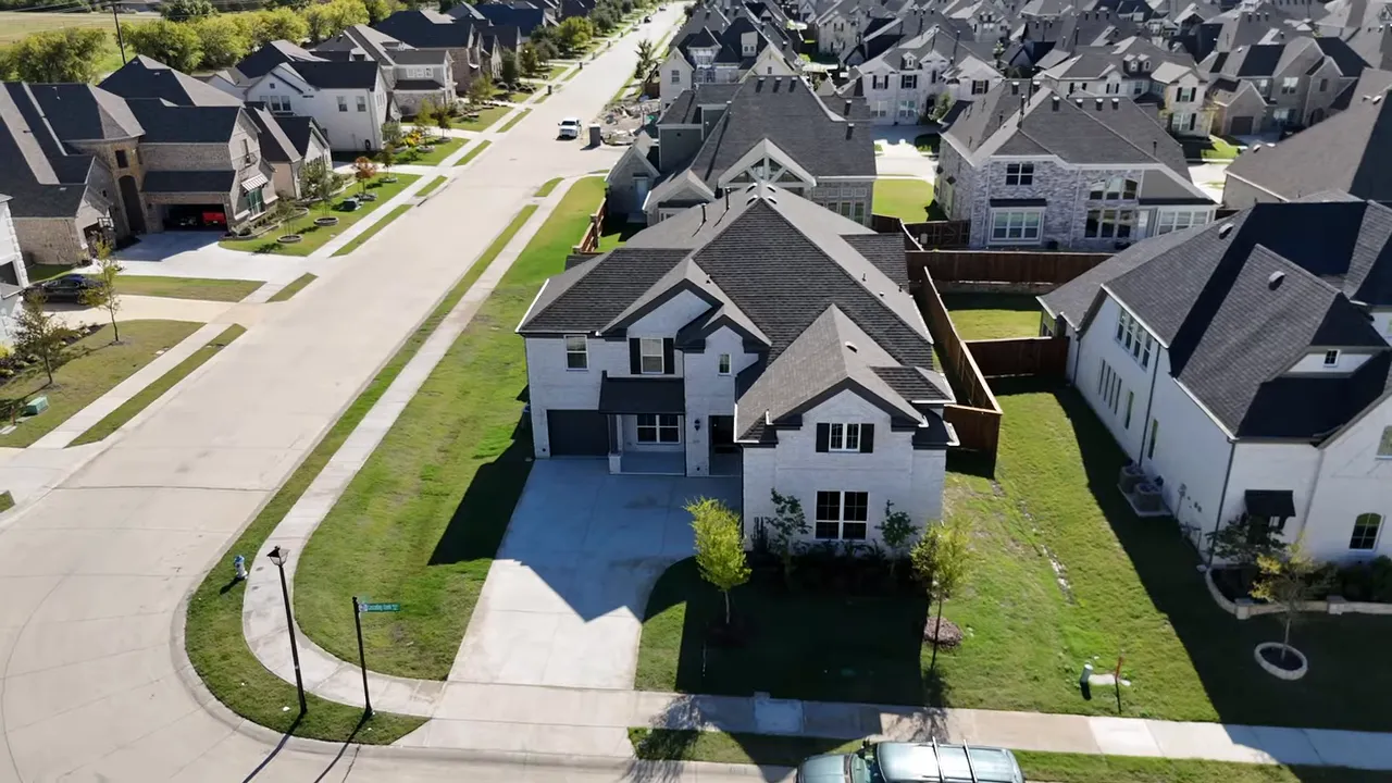 Drone shot of Grand South Pointe home showing three-car garage, backyard and neighborhood