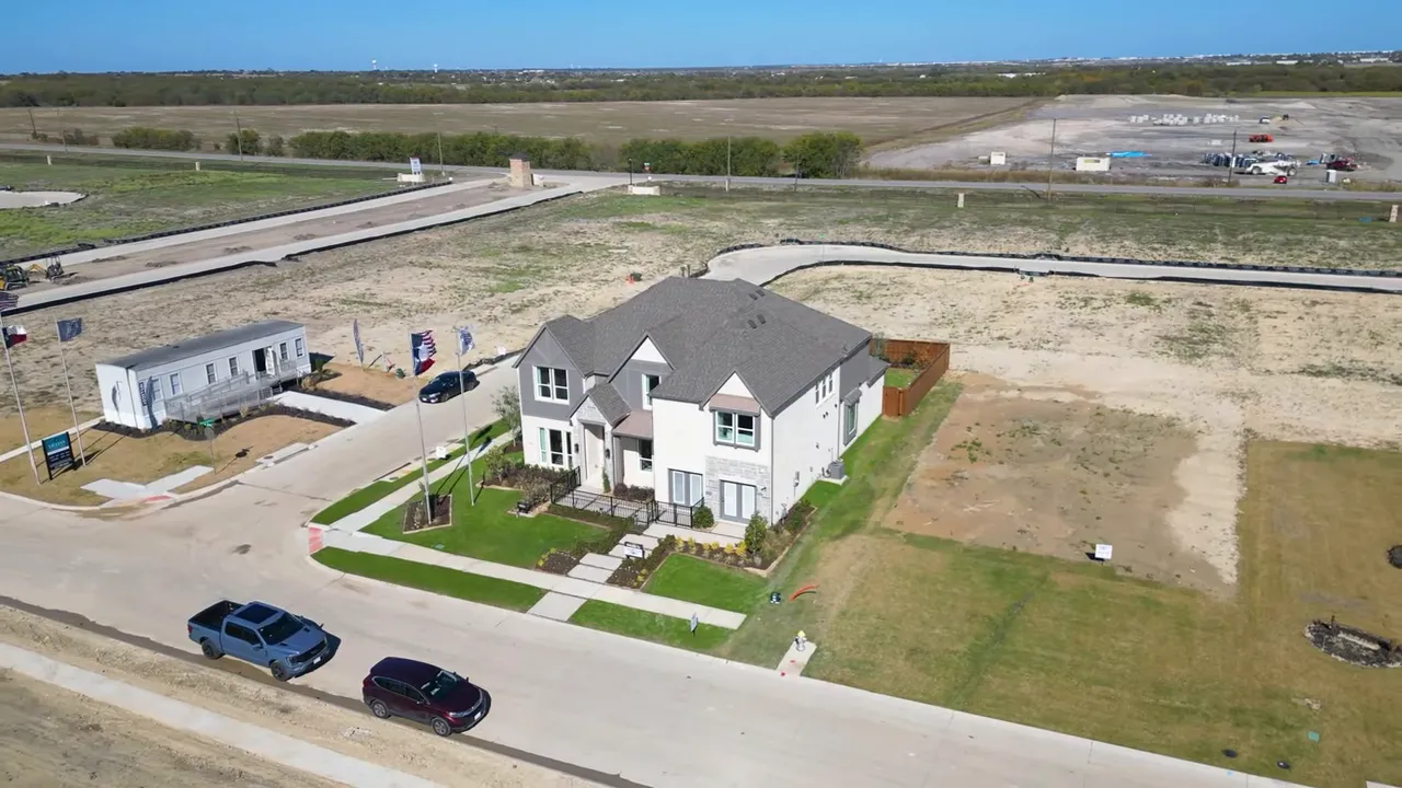 Presenter seated in green-lit studio with 'here's how to' text overlay and shelf of collectibles behind