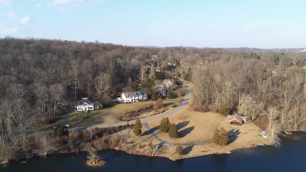 Scenic shaded road through tall trees in Mendham Township showing mature landscaping and a house set back from the road.