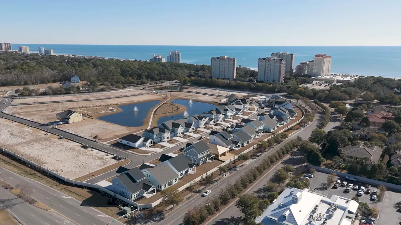 Full front exterior of a new-construction home with covered porch, two-car garage, landscaped planting and presenter by the entry