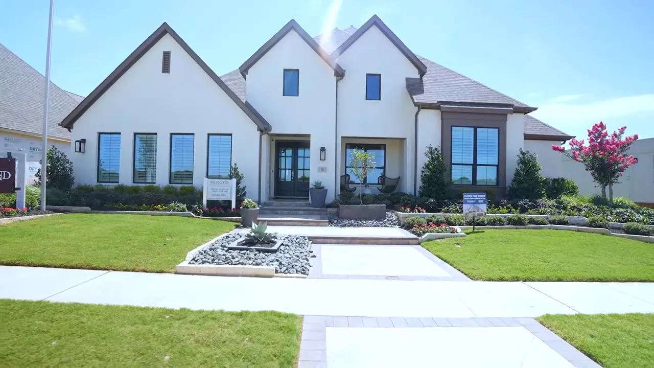 Front exterior of a white single story home with dark roof and landscaped walkway