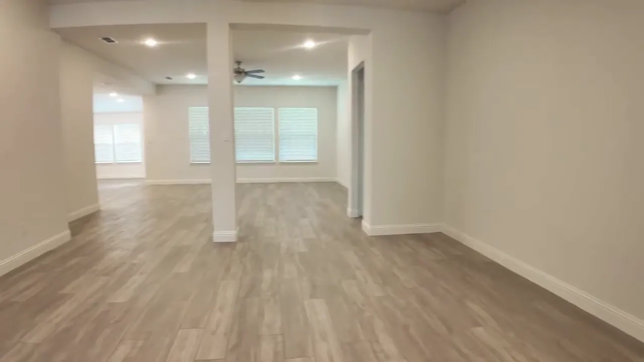 Large open flex room with wood look flooring white columns and windows
