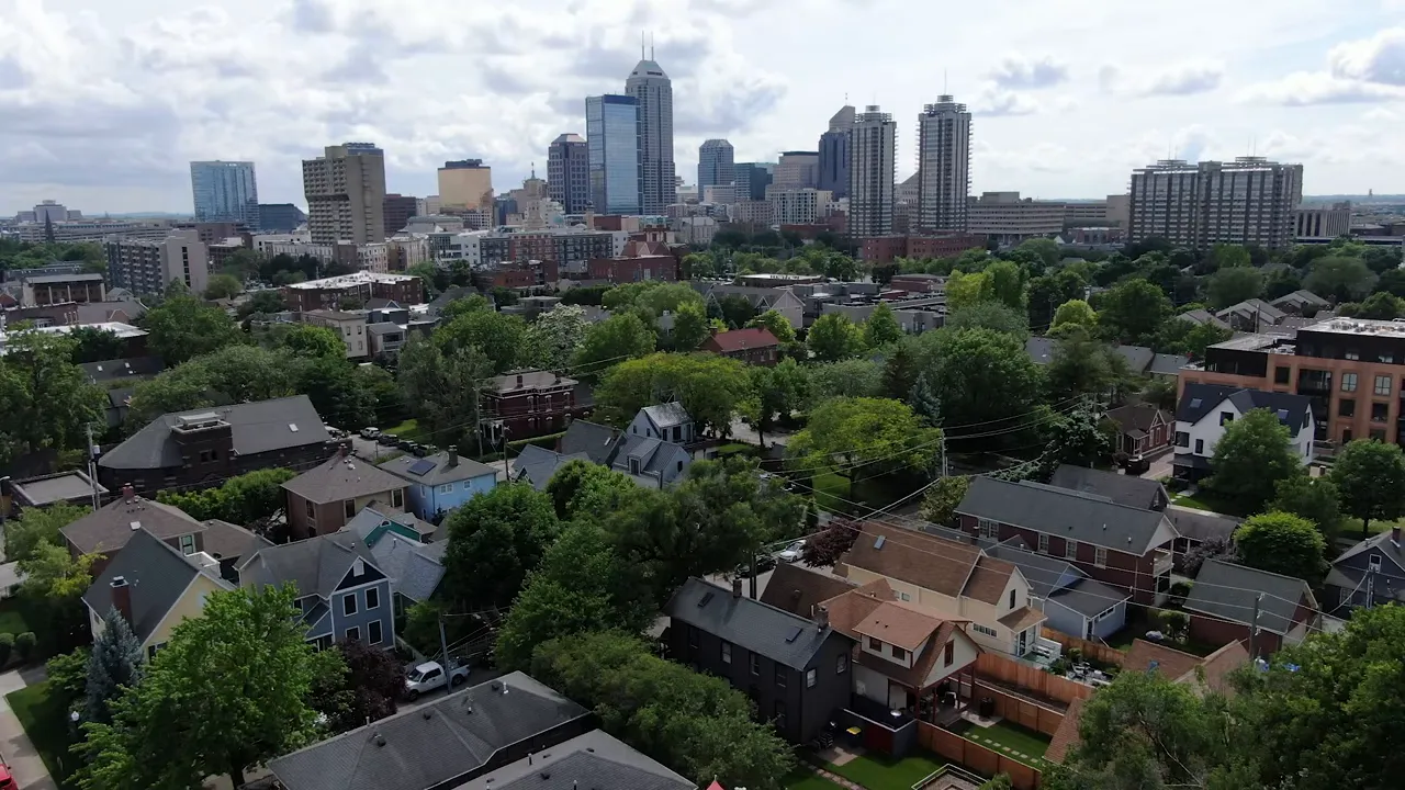 Presenter in studio with 'Living in Indianapolis' sign, speaking into a microphone