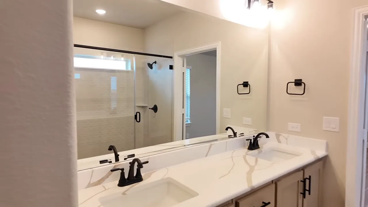 Double vanity with large mirror white countertop and dark faucets