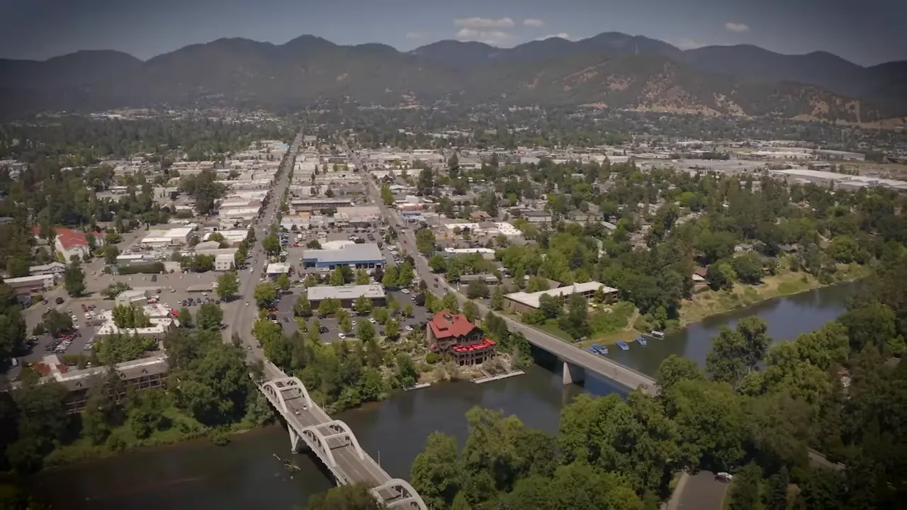 G Street downtown Grants Pass showing shops, trees, and street traffic