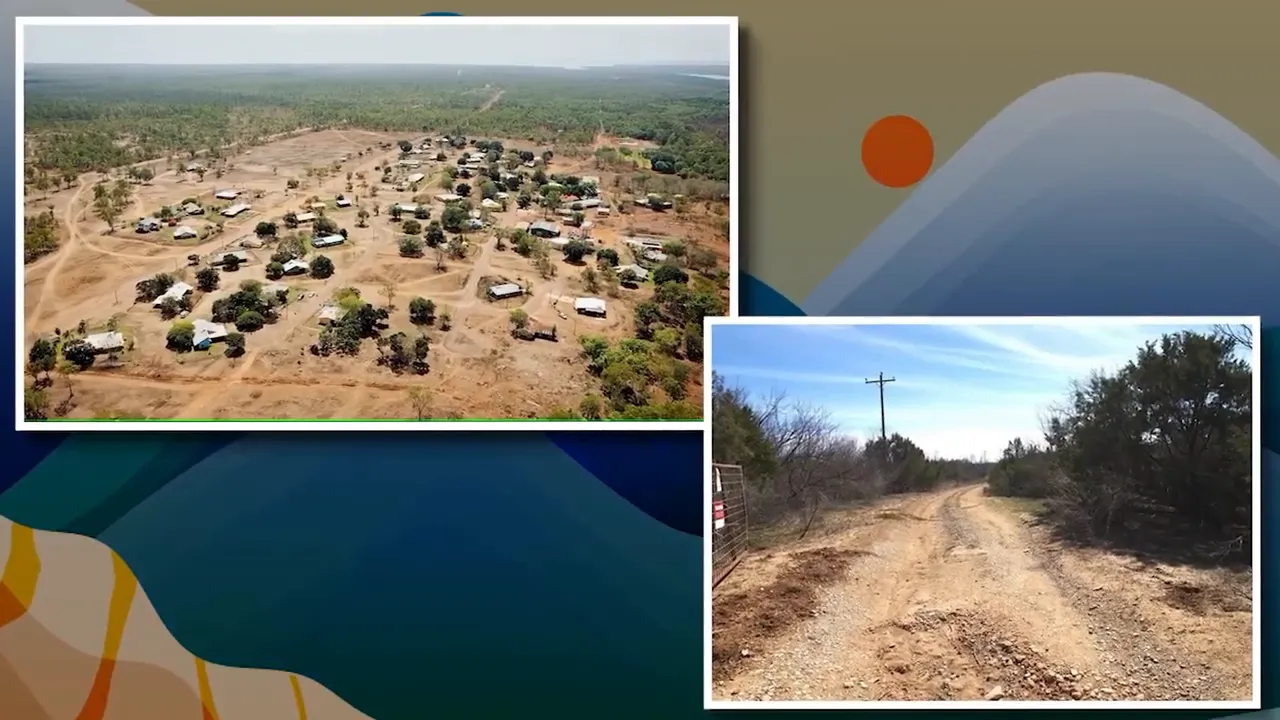 Wide shot of paved road with curb and vacant grassy parcel with utility stakes and hills behind, presenter visible