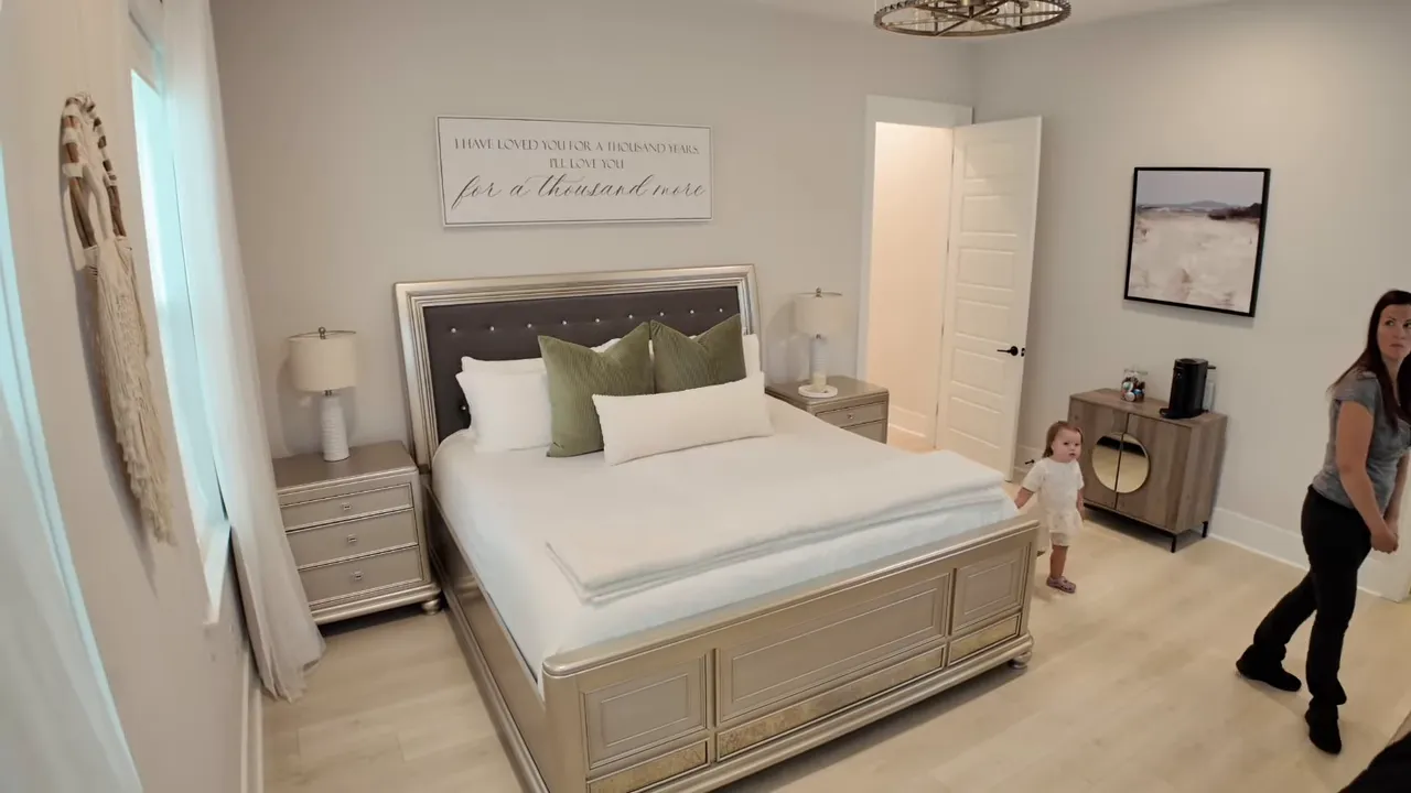 First floor primary bedroom with large bed, dresser, and doorway to bath hall