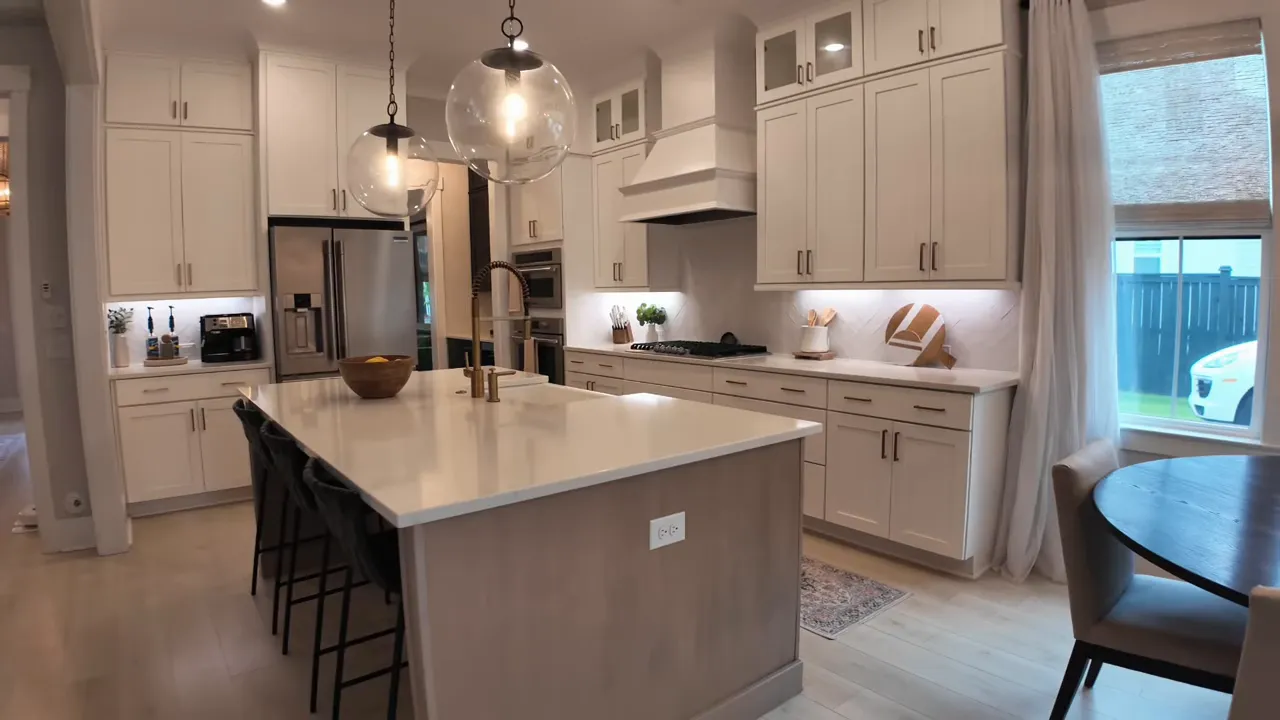 Large kitchen with long island, pendant lights, white cabinets, and stainless steel appliances
