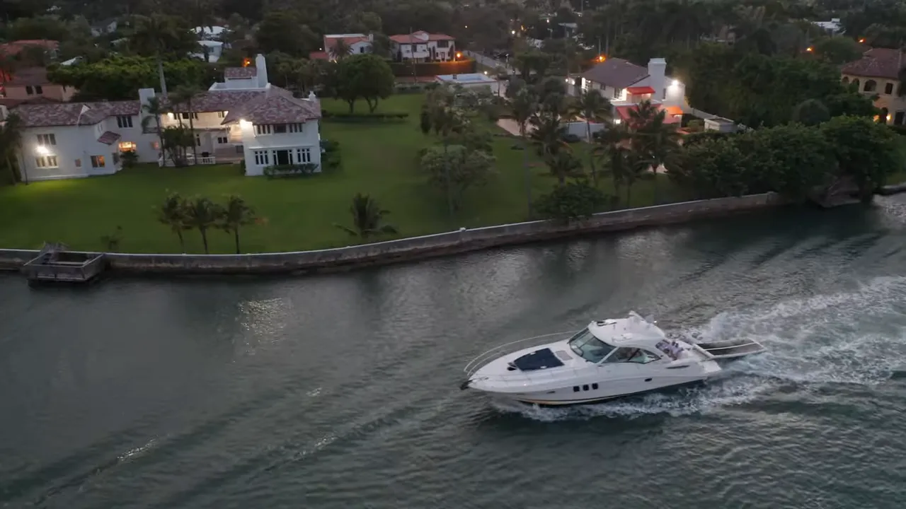 Couple strolling along a Florida beach at sunset with reflections on wet sand and boats offshore