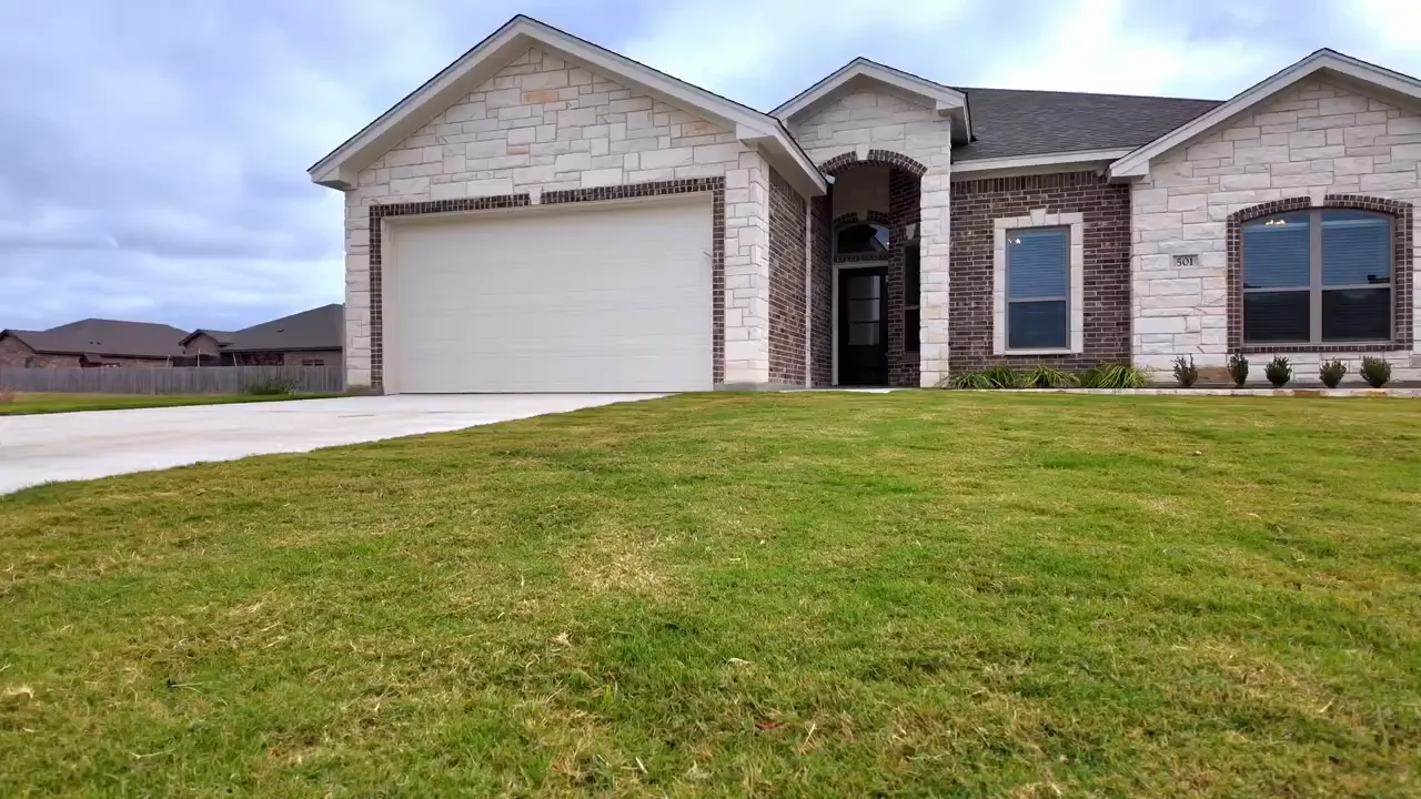 Front porch with brick and stone columns and glass front door at a Turtle Creek home with a presenter standing in the entryway