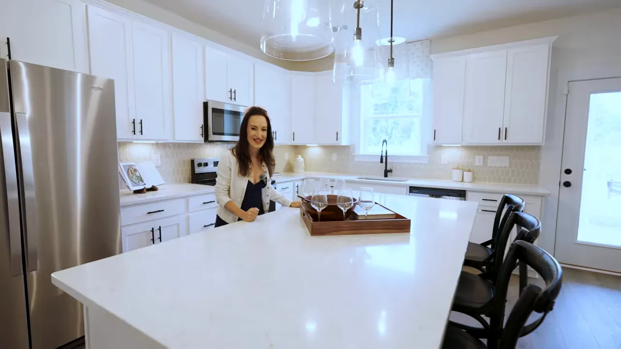 Wide view of a modern kitchen with white cabinetry and island seating area