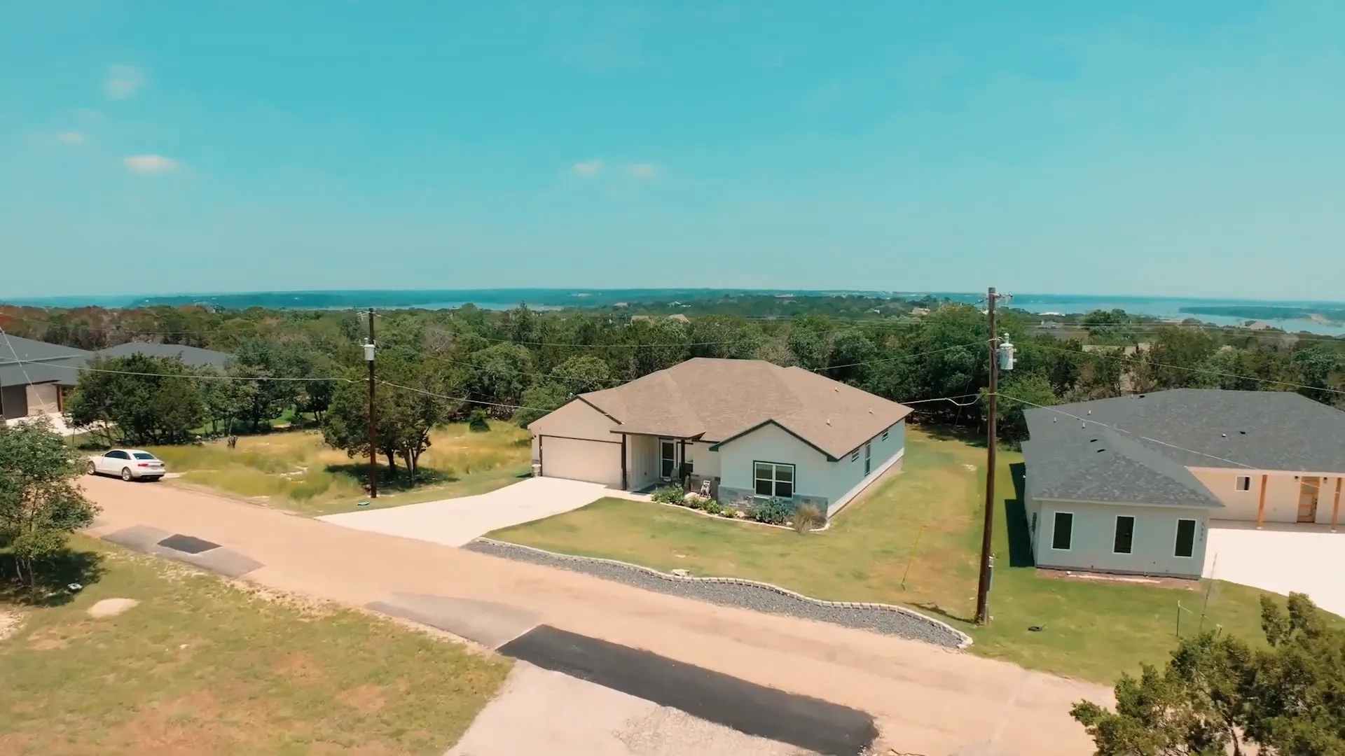 Aerial view of a neighborhood in Tanglewood with dense trees and a lake in the background