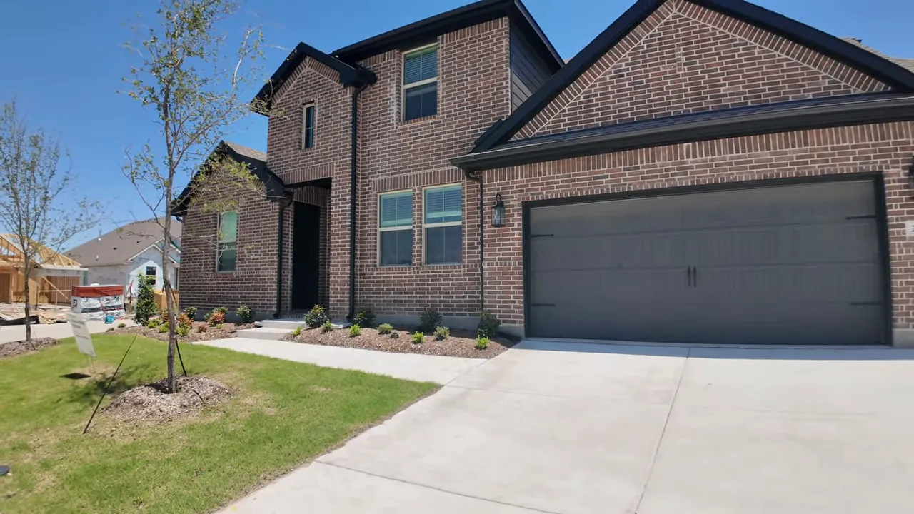 Dark brick two story home with three car garage and landscaped front yard