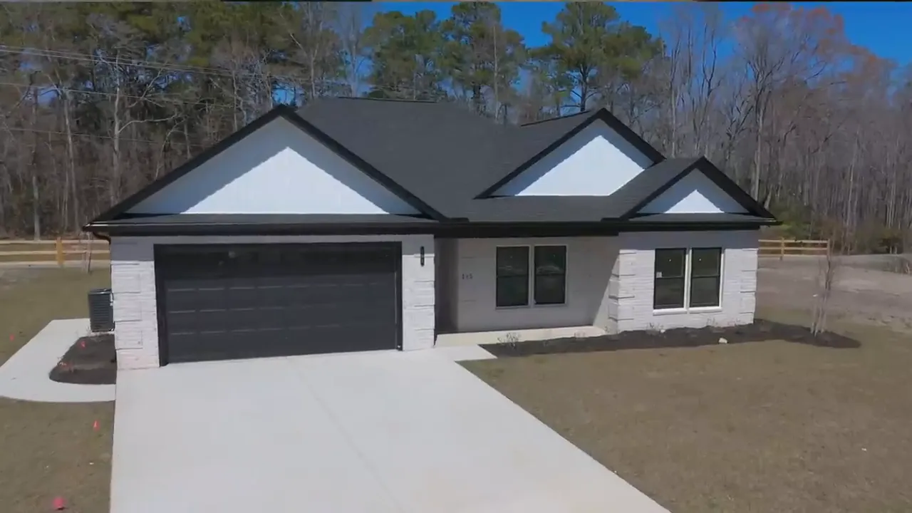Large open kitchen and living space in unfinished model with blue protective covering on island countertops
