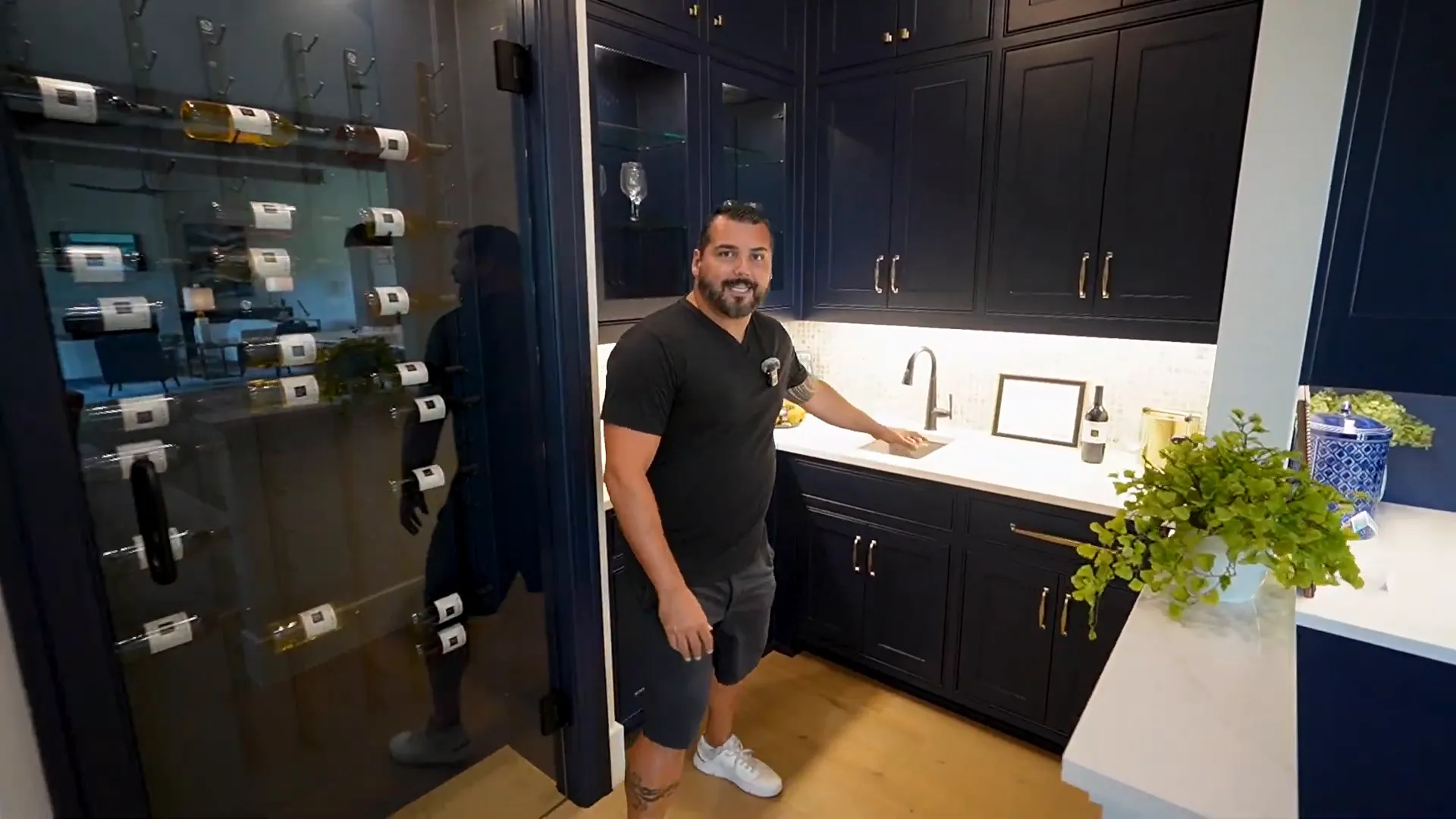 Bar area with navy cabinetry, sink, and wine room with glass door