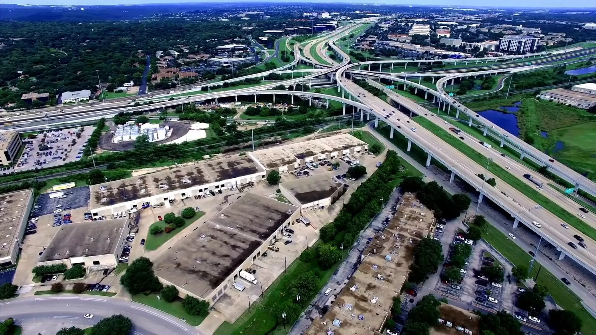 Wide suburban multi-lane road seen from a car with houses and power lines at the roadside
