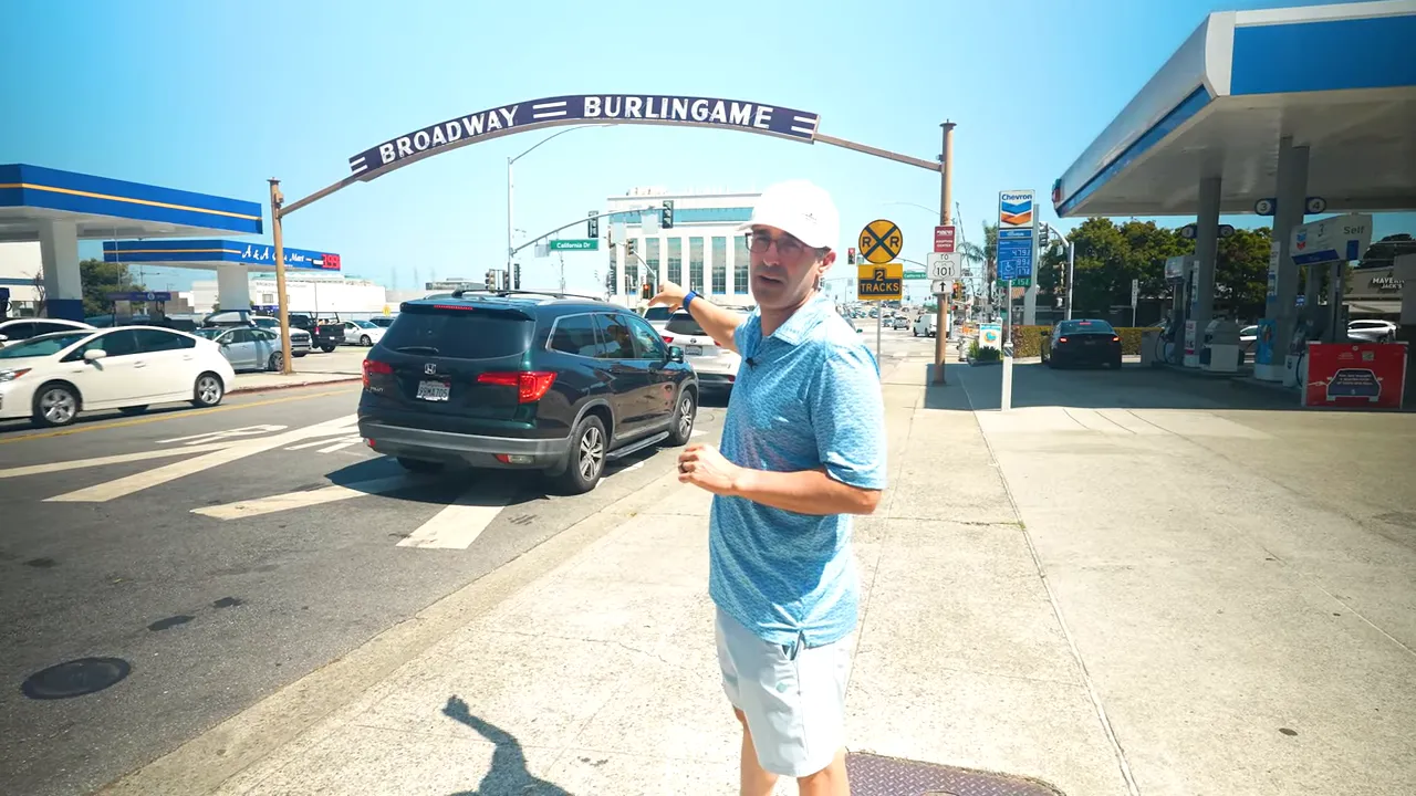 Broadway storefront with awnings, sidewalk and person walking past shop at 1165 in Burlingame Terrace