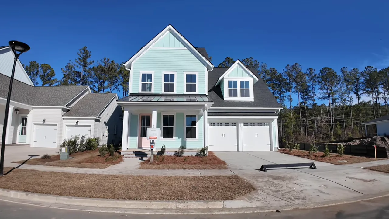Open front door with mint-green hardy plank siding, a person carrying a child entering and a presenter at the doorway