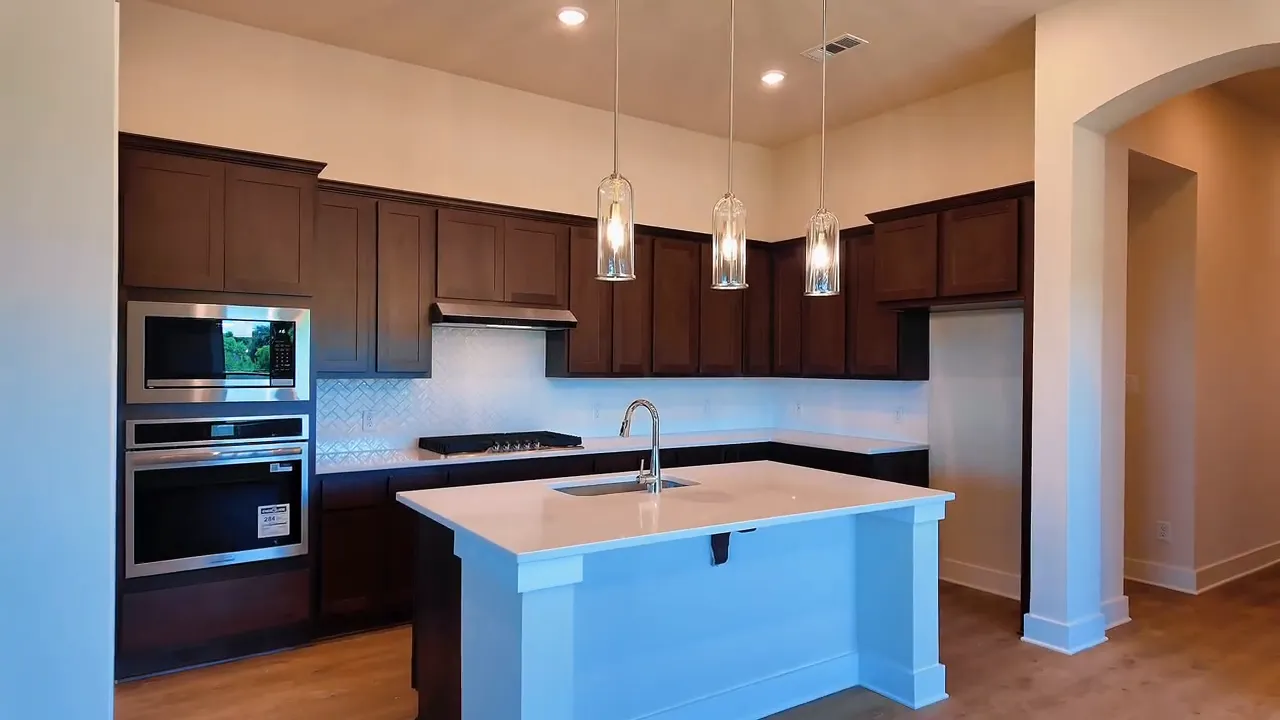 Kitchen with dark cabinetry, gas range, tile backsplash, and large island in a new construction home