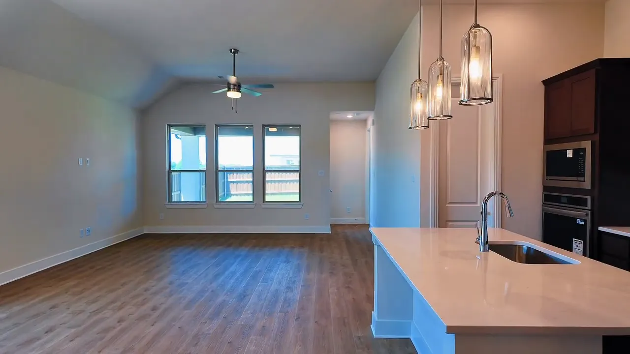 Living room with large windows and warm LVP flooring in a new construction home