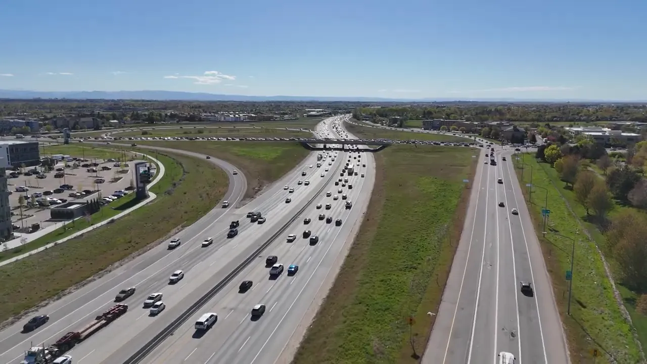 Cars driving through heavy snowfall on a slushy Boise road with accumulation at the curb.