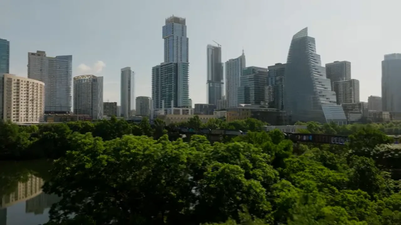 Presenter standing on an Austin street talking to camera with city buildings and light traffic behind.