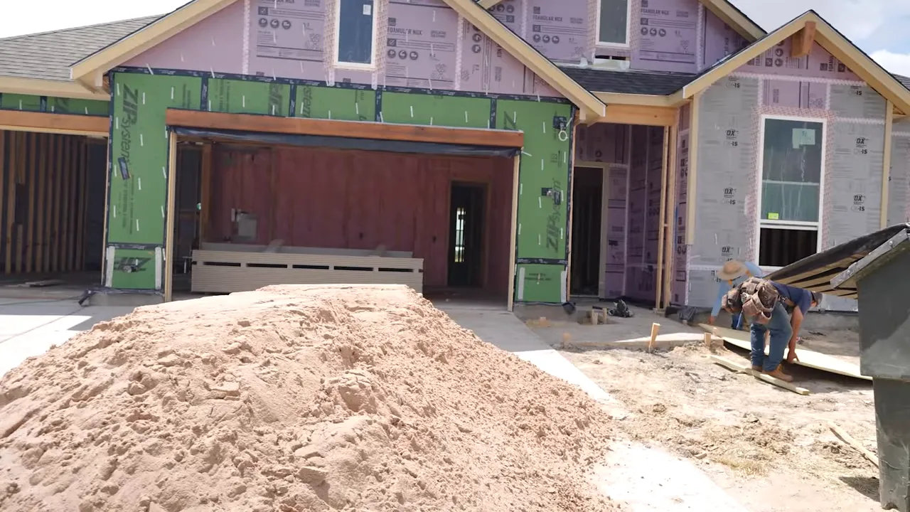 Exterior view of new construction during pre-drywall phase showing open framing and installed sheathing