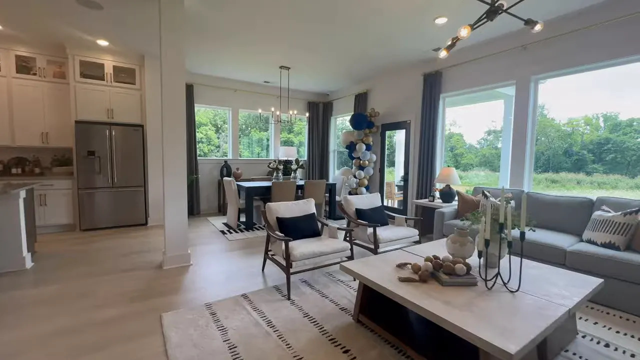 Open living, dining, and kitchen layout with large windows and glass door