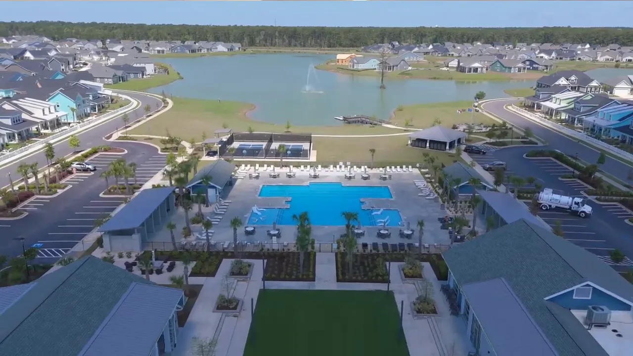 Aerial view of community pool, clubhouse, and surrounding homes