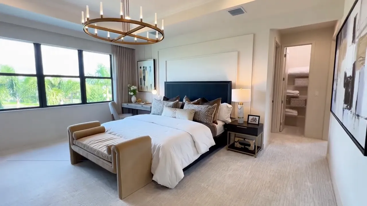 Luxury owner’s suite bedroom with large windows and modern furnishings in a GL Homes Polaris model at Avenir Palm Beach Gardens