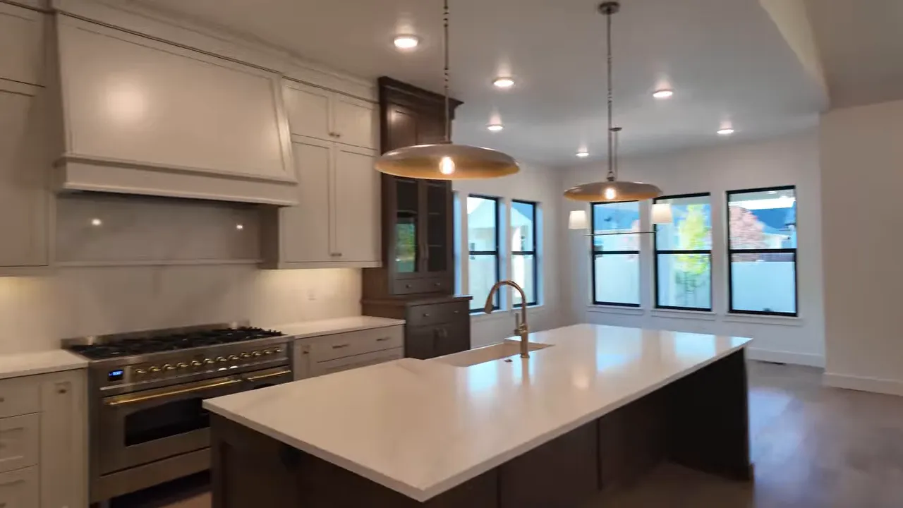 Gold kitchen faucet running over a large white island sink