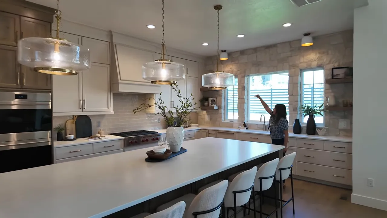 Close view of a bathroom entry with textured shower tile and a doorway to a walk-in closet; presenter gestures toward the tile