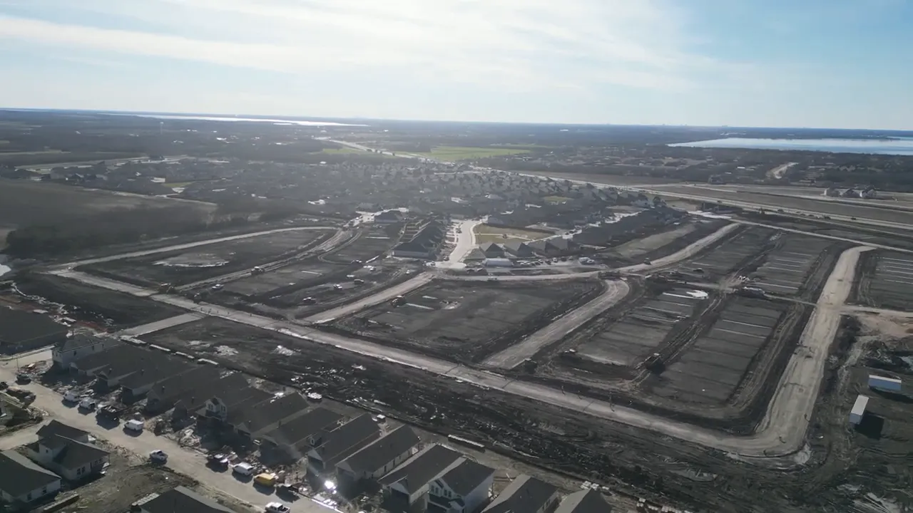 Realtor walking through Elevon construction site showing empty lots, new road, and utilities in the background.