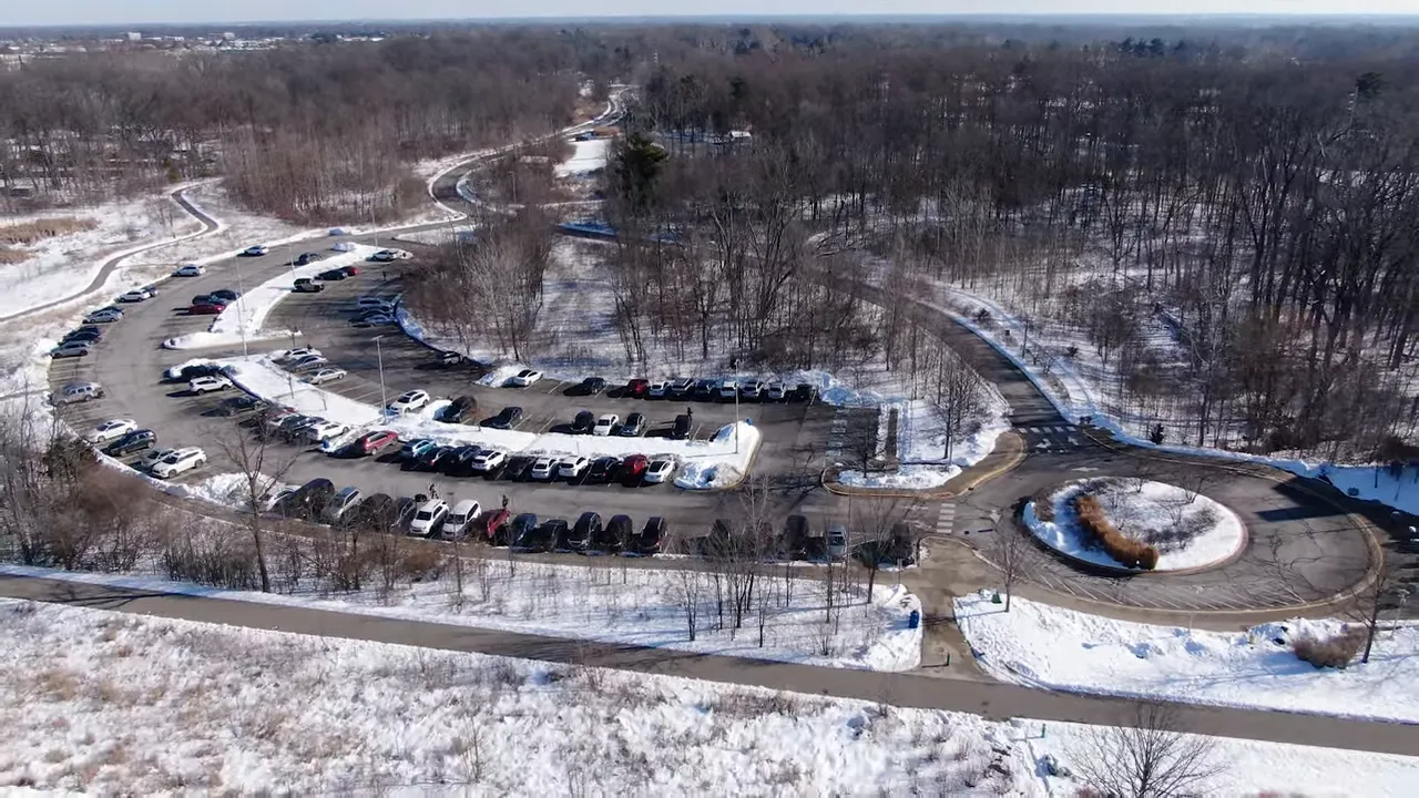 Aerial view of a snow-covered park, trail and empty parking area in Indianapolis.