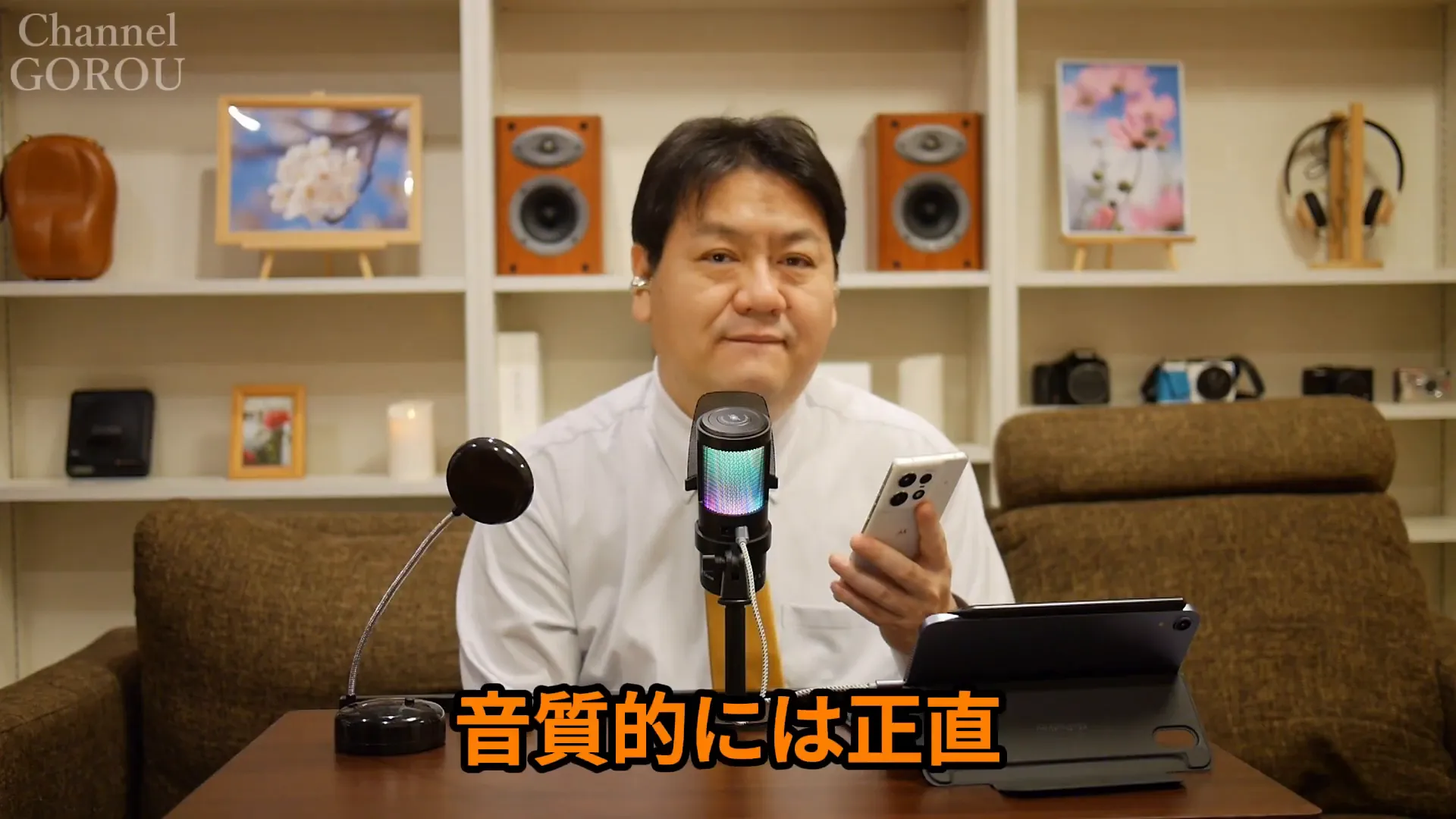 中央のマイク越しに正面を向くレビュワー。画面下に『音質的には正直』の大きなテロップがある。