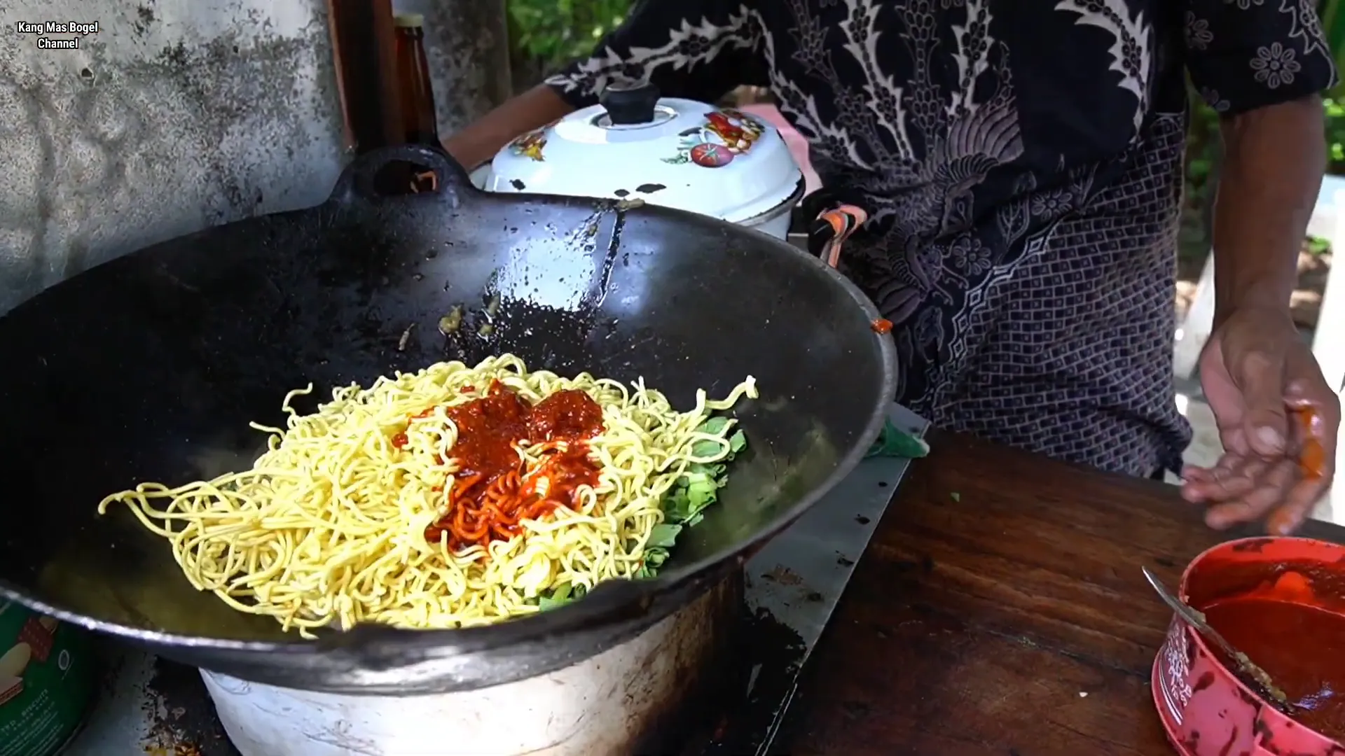 Pak Ridwan sedang menggoreng nasi goreng dengan porsi besar