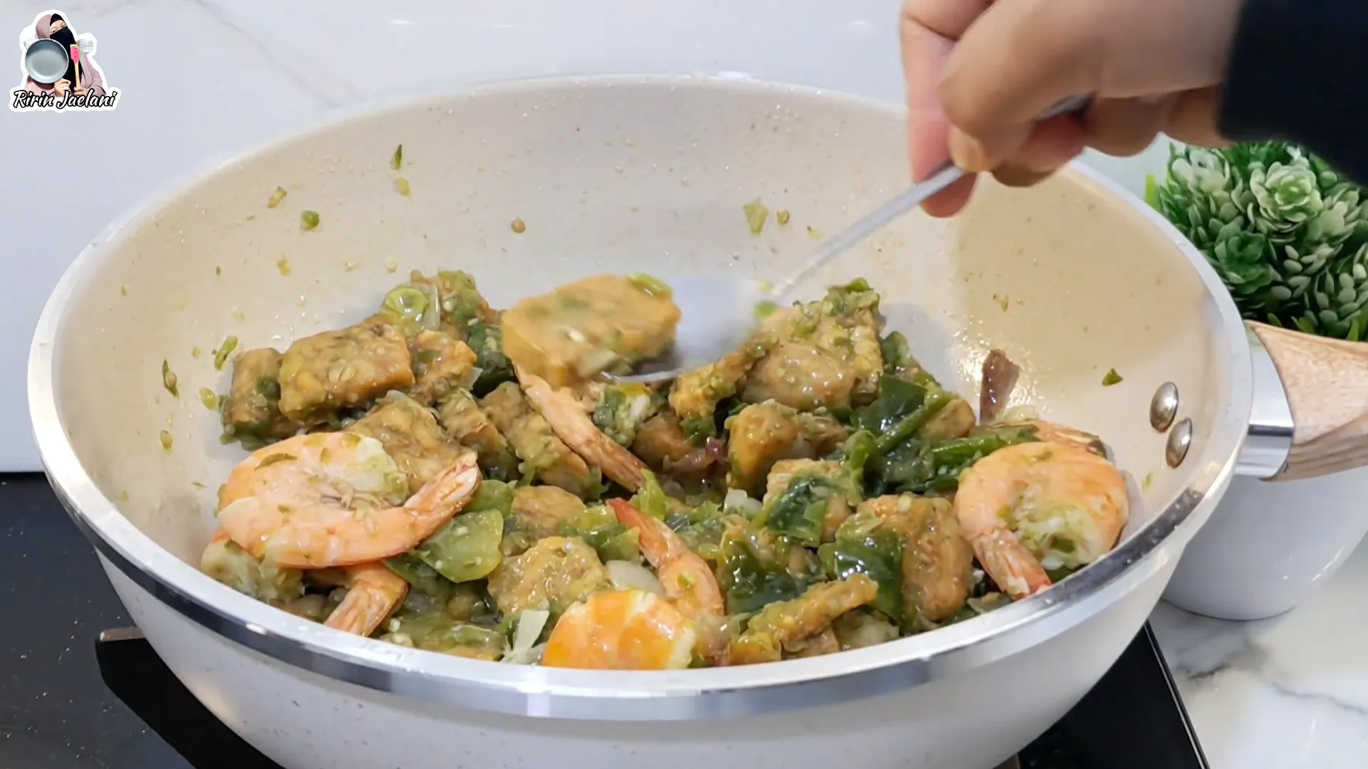 Mengaduk tempe dan udang bersama sambal ijo dalam wajan