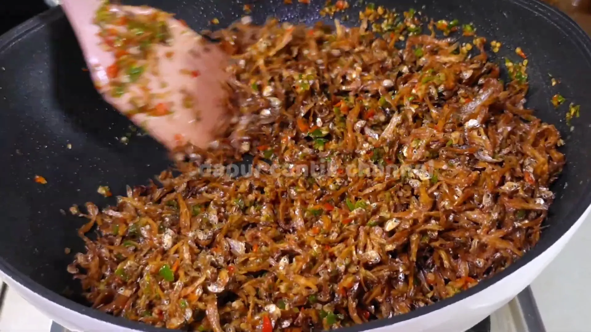 Mencampurkan teri goreng ke dalam bumbu oseng Lombok rawit