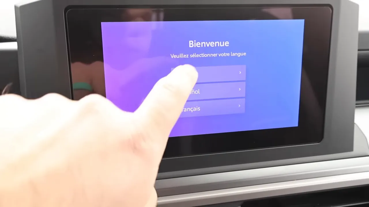 Touchscreen infotainment showing language selection with finger tapping the display