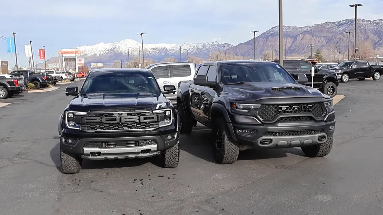 Front view of a Ford Ranger Raptor (left) and Ram T-Rex (right) parked side-by-side