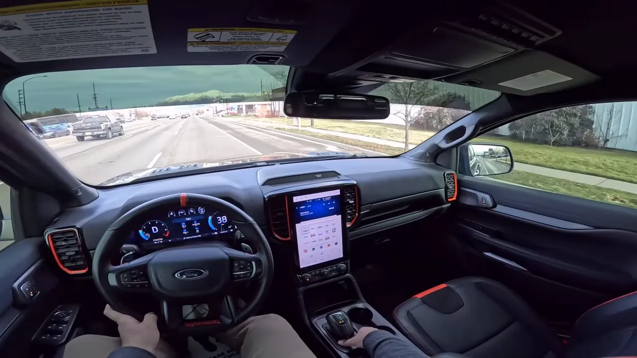 Driver's POV interior of a Ford Ranger Raptor showing wide dashboard, digital instrument cluster and portrait infotainment