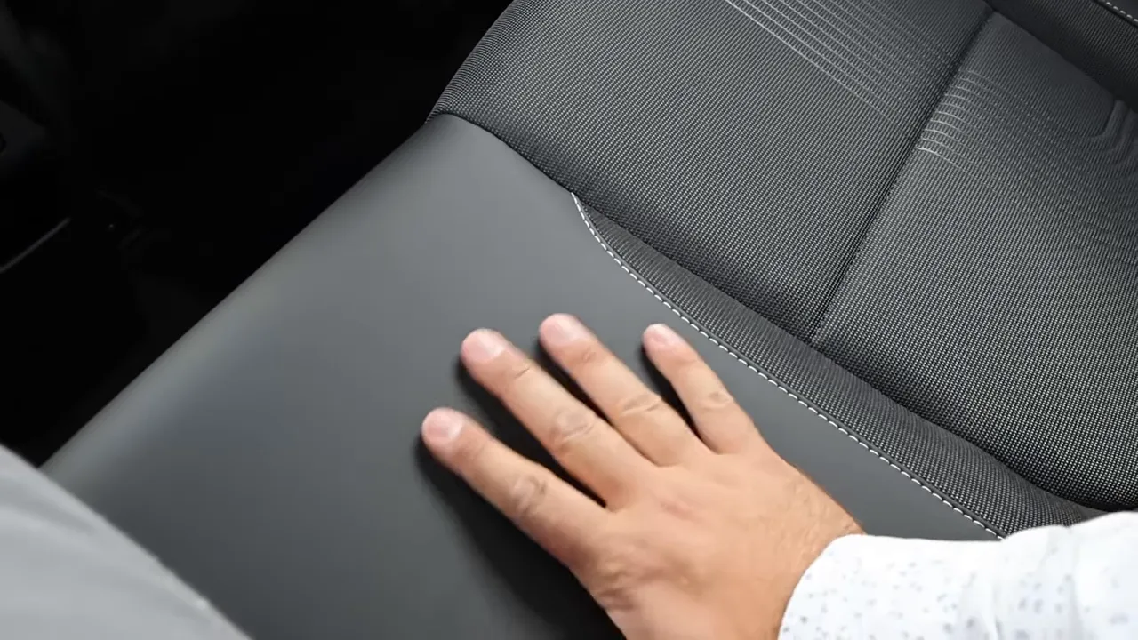 Hand touching Hyundai Venue seat showing soft-touch material, cloth insert and white contrast stitching