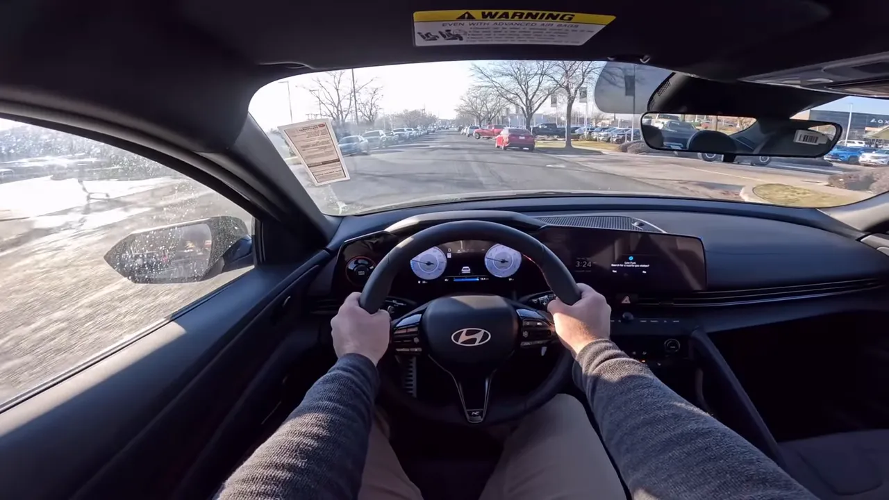 Clear centered driver's-eye interior view of the 2026 Hyundai Elantra N-Line showing the steering wheel, digital gauges and a straight road ahead.